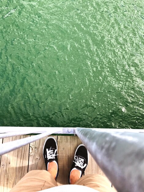 Photo low section of man standing on bridge over sea