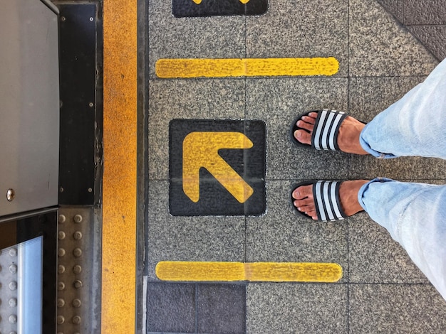 Photo low section of man standing by arrow symbol