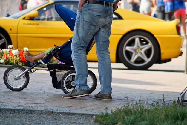 Photo low section of man standing by baby carriage on footpath