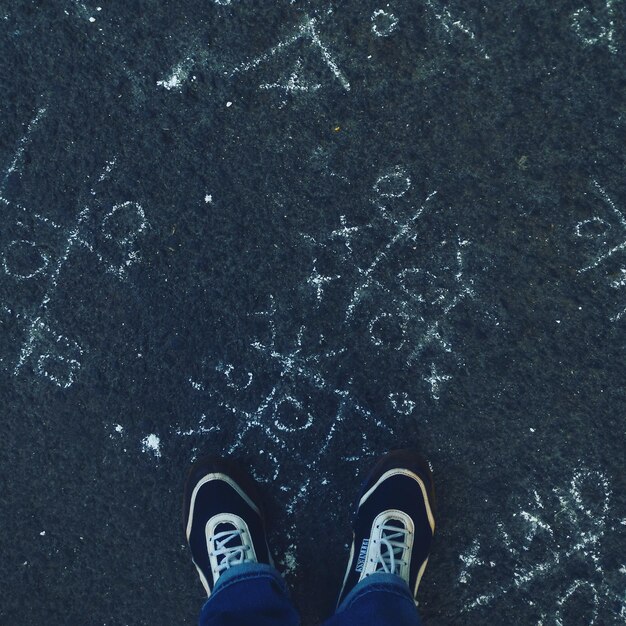 Photo low section of man standing by chalk drawing on road