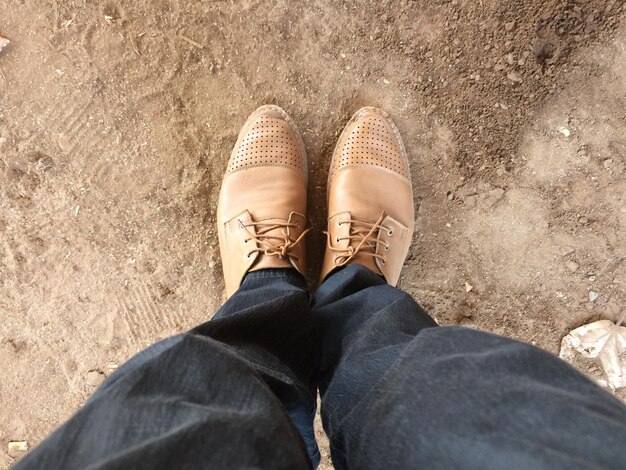 Foto sezione bassa di un uomo in piedi su una strada di terra