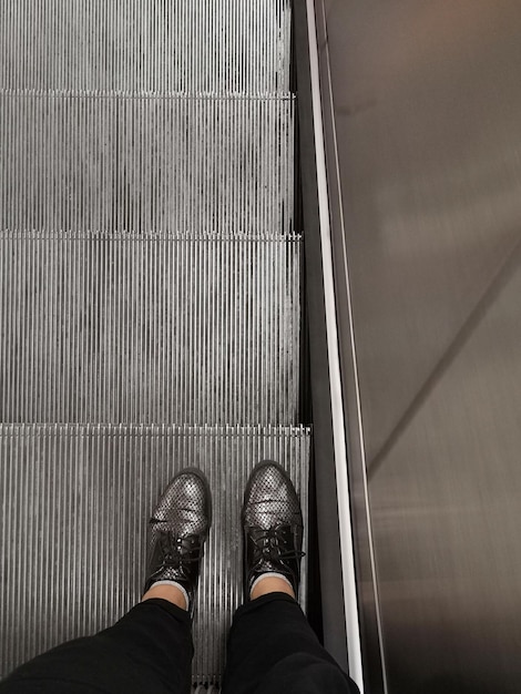 Photo low section of man standing on escalator