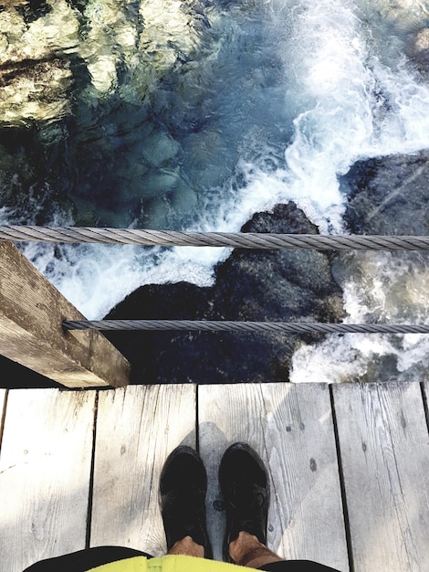 Photo low section of man standing on footbridge over river