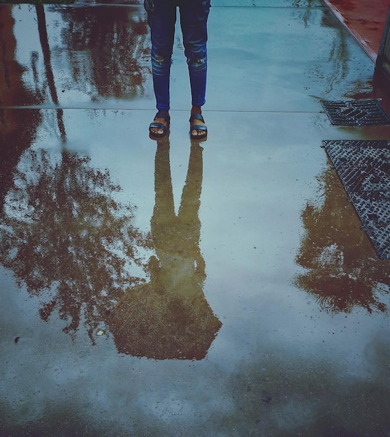 Photo low section of man standing on puddle