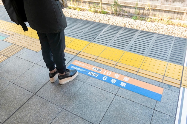日本の東京の鉄道駅のプラットフォームに立っている男性の下部