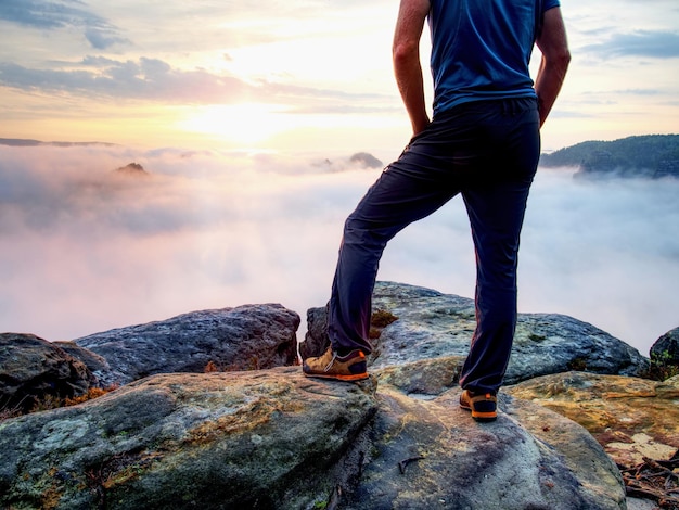 Foto sezione bassa di un uomo in piedi su una roccia contro il cielo durante il tramonto