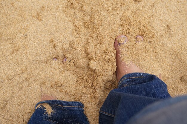 Low section of man standing on sand at beach