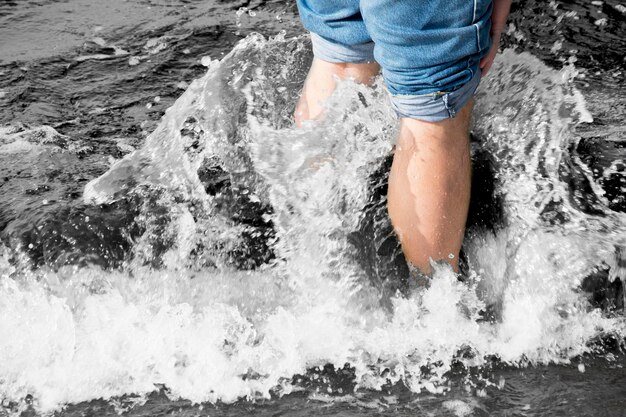 Low section of man standing in splashing sea