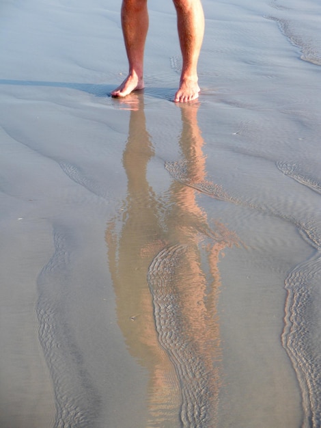 Photo low section of man standing on wet beach