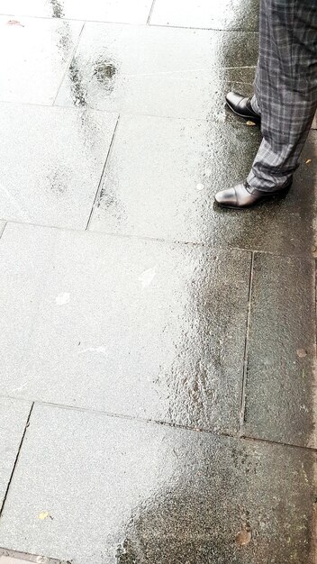 Foto sezione bassa di un uomo in piedi su un sentiero bagnato