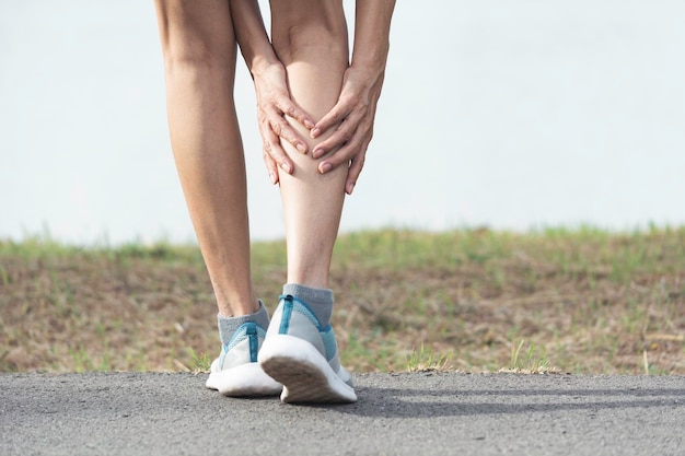 Low section of man suffering from knee pain on road