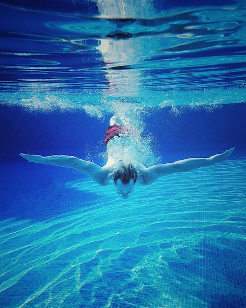 Low section of man swimming in pool