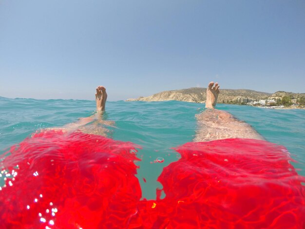 Photo low section of man swimming in sea against clear sky