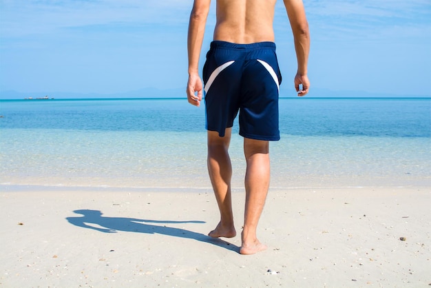 Low section of man walking at beach