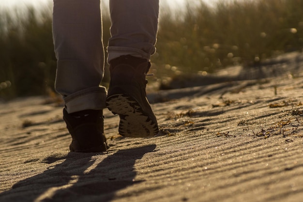 low section of man walking on beach