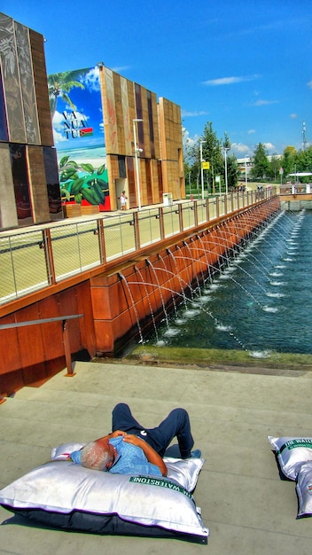 Low section of man walking on water in city against sky