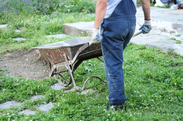 Low section of man walking with wheel barrow in grass