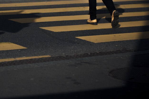 Low section of man walking on zebra crossing