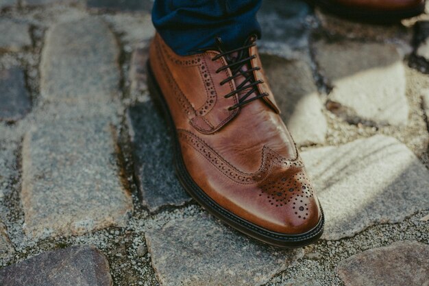 Foto bassa sezione di uomo che indossa una scarpa di pelle marrone sul sentiero