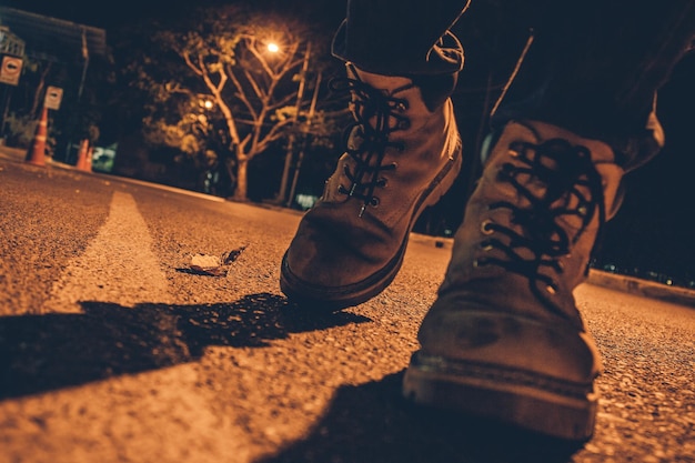 Нижняя часть человека, носящего обувь и идущего по улице ночью.