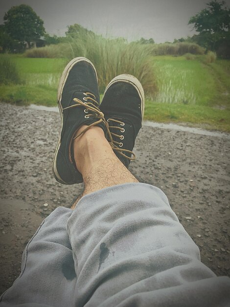 Photo low section of man wearing shoes while relaxing at park