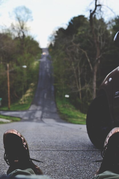 Photo low section of man wearing shoes while sitting on road by car