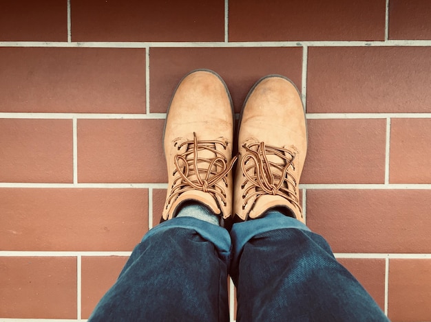 Photo low section of man wearing shoes while standing on tiled floor