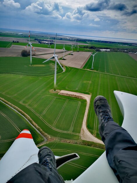 Foto sezione bassa dell'uomo sul mulino a vento in un campo agricolo