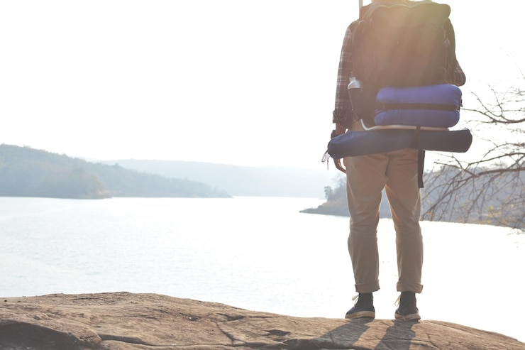 Photo low section man with backpack standing on rock by river against clear sky