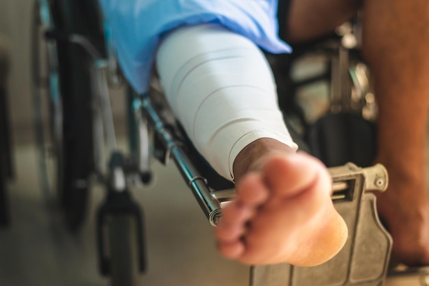 Low section of man with bandage sitting on wheelchair