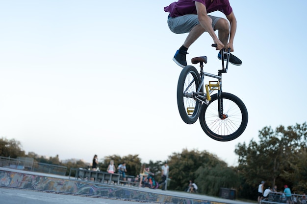 明るい空の前でスタントを演じている自転車に乗った男性の低い部分