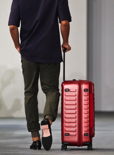 Photo low section of man with luggage walking on road