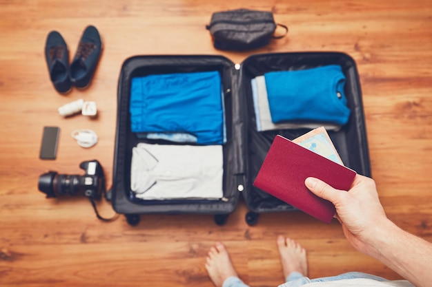 Foto sezione bassa dell'uomo con il passaporto in piedi accanto al bagaglio sul pavimento