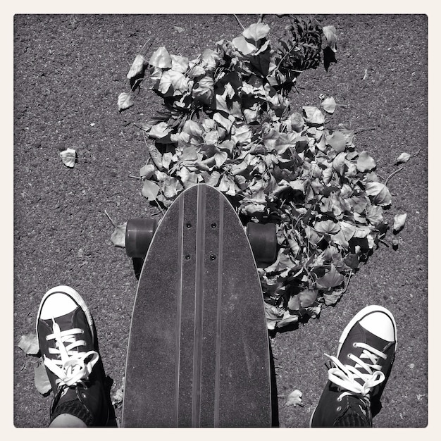 Foto sezione bassa di un uomo con uno skateboard in strada