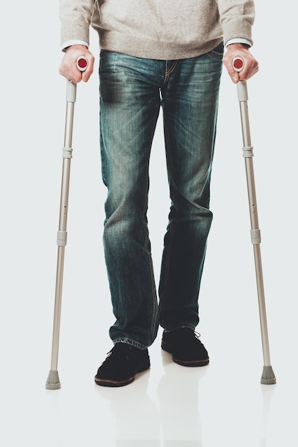 Low section of man with walking canes against white background