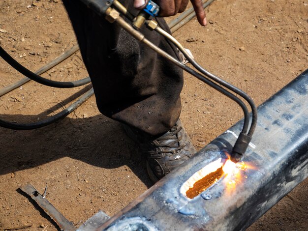 Foto sezione bassa del lavoratore manuale che riscalda il metallo all'aperto