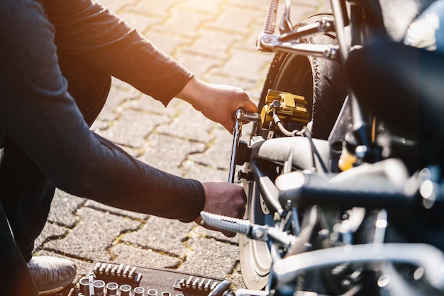 Foto sezione bassa di un meccanico che ripara una motocicletta in strada