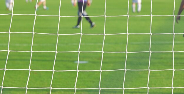 Foto sezione bassa di uomini che giocano a calcio sul campo vista attraverso il palo della porta