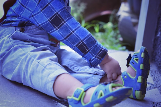 Фото Нижняя часть мальчика в обуви, сидящего на улице