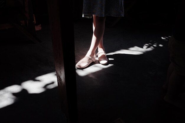 사진 어두운 방에서 바닥에 서 있는 동안 신발을 입은 소녀의 낮은 섹션