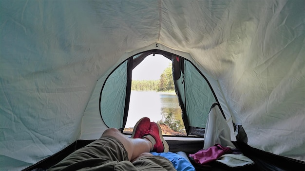 Фото Нижняя часть человека отдыхает в палатке на берегу озера