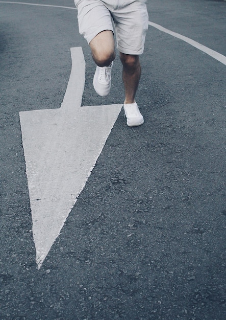 写真 矢印の道路標識に沿って走っている男の下部