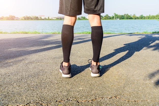 写真 湖のそばの道路に立っている男性の下部