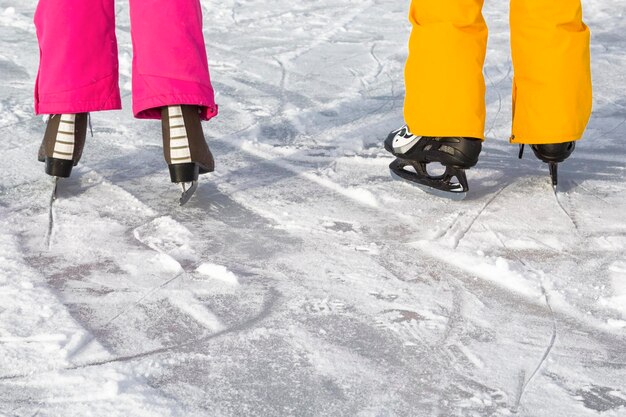 写真 雪の上でアイススケートを着ている人々の下部