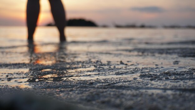 Фото Нижняя часть человека на пляже во время захода солнца