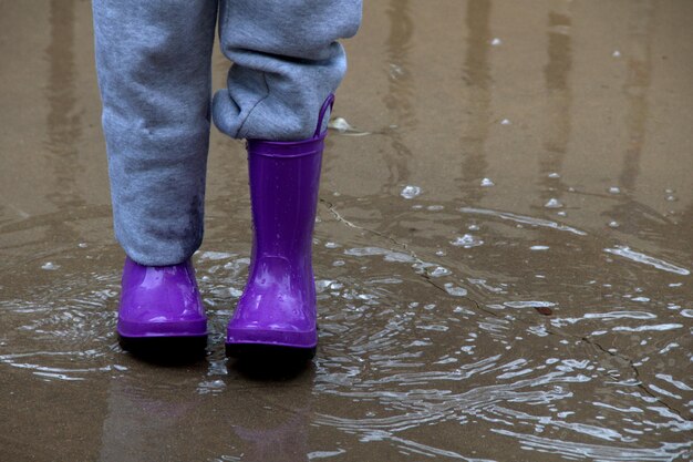 写真 雨季の路上に立っているブーツを履いた人の下部