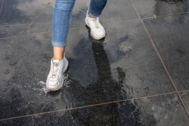 写真 湿った歩道に立っている女性の下部