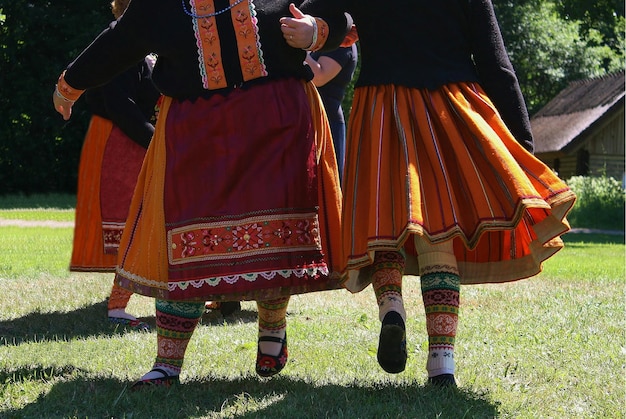 Low section of people performing traditional dance on grassy field