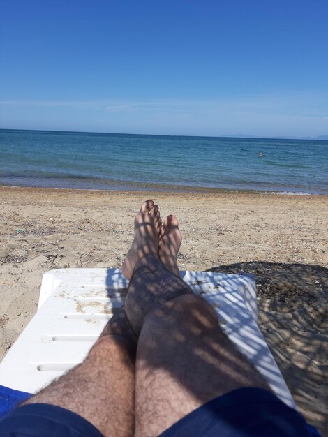 Foto sezione bassa di persone che si rilassano sulla spiaggia