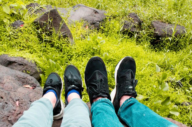 Low section of people sitting on rock by grassy field